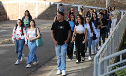 Na imagem há, aproximadamente, 23 estudantes da UNIFAL-MG caminhando na Universidade, durante à Acolhida aos Calouros 2024/2. Todos eles estão de calça, tênis e camiseta. Há uma diversidade étnica presente na imagem. Fim da descrição.